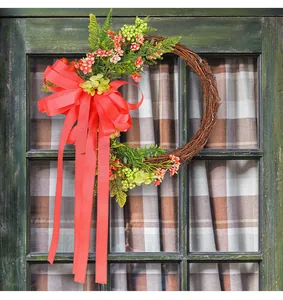 Decorative floral wreath featuring a large red bow and streamers on a rustic wooden door.