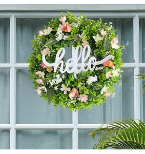 Green eucalyptus wreath detail with pink flowers and a white wooden hello sign.