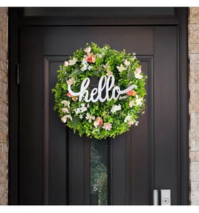 Spring eucalyptus wreath with white Hello sign hanging on a dark modern front door.