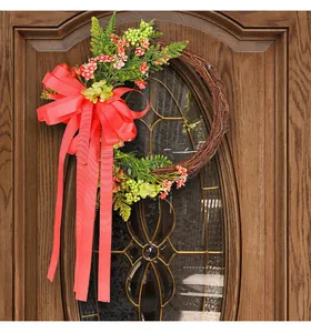 Decorative vine wreath with large red bow hanging on a rustic wooden door scene.