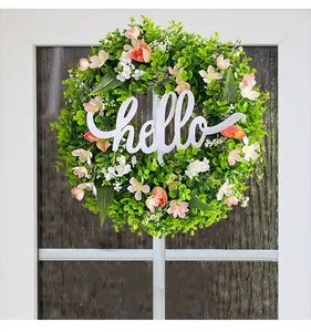 Detailed view of artificial eucalyptus wreath with white 'hello' sign and pink flowers