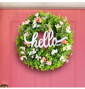 Detail of decorative spring eucalyptus wreath featuring a white hello sign on a pink door