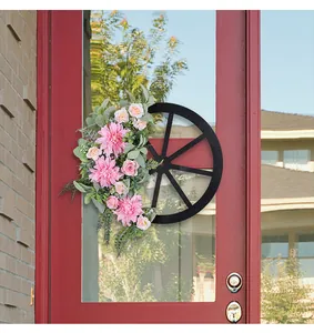 Close-up detail view of pink dahlia and rose floral wreath on a black wagon wheel frame