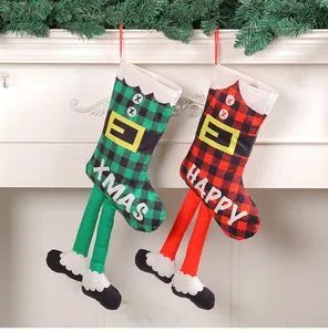 Calze di Natale creative a scacchi con lunghe gambe appese a una mensola del camino bianca.