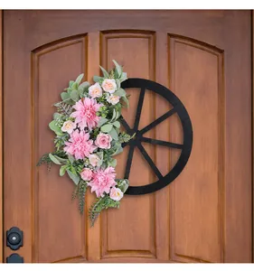 Detail view of a pink dahlia wagon wheel wreath hanging on a rustic wooden door.