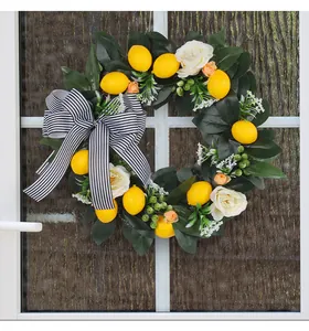 Artificial lemon flower wreath with a striped bow decoration hanging on a white glass door.