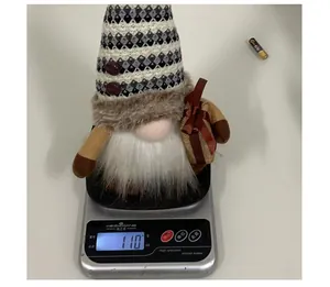 Detalle de un gnomo de peluche luminoso en una báscula digital que pesa 110g