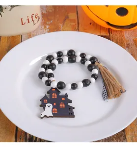 Macro view of Halloween wooden bead garland with ghost haunted house charm on white plate