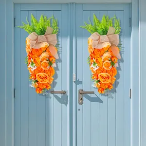 Pasen wortelvormige bloemenkrans met oranje rozen en jute strik aan de mooie blauwe deur