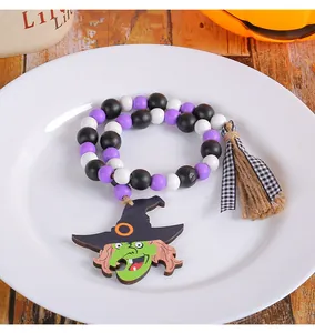 Close-up of Halloween wooden bead garland with green witch pendant and jute tassel