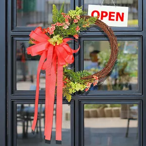 Rustic vine wreath with large red ribbon bow and faux flowers on glass door background