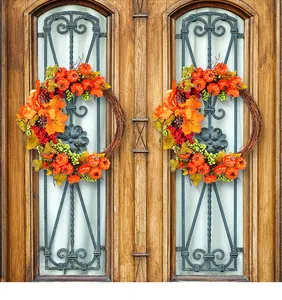 Dos coronas de cosecha de otoño con calabazas y hojas de arce colgadas en una puerta de madera