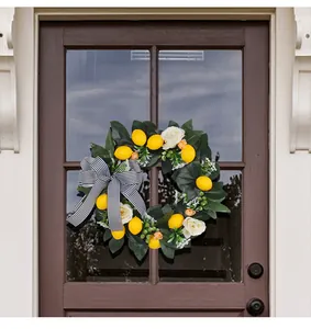 Summer lemon wreath with black and white bow hanging on a brown wooden front door