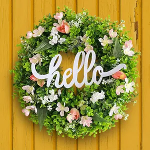 Spring eucalyptus wreath with pink flowers and a white hello sign on yellow wood