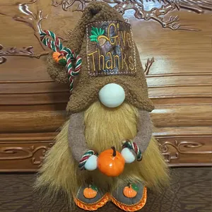 Detailed view of an autumn gnome plush holding a small pumpkin with Give Thanks embroidery