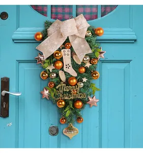 Festive teardrop Christmas swag with gold ornaments and burlap bow on blue door