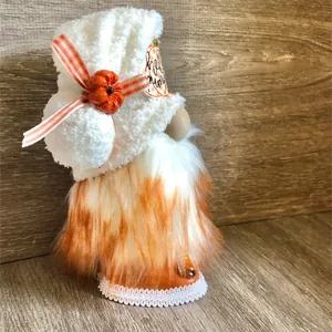 Close-up detail of autumn faceless gnome with white fuzzy hat and pumpkin decor