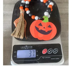 Detailed view of Halloween wooden bead garland with pumpkin tag weighing 37g on a scale.