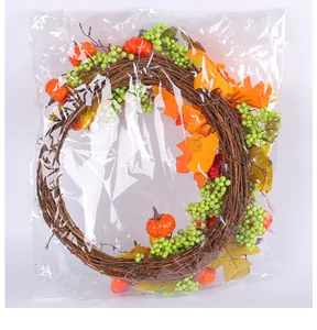 Vista detallada de la corona de cosecha de otoño con calabazas en empaque transparente.
