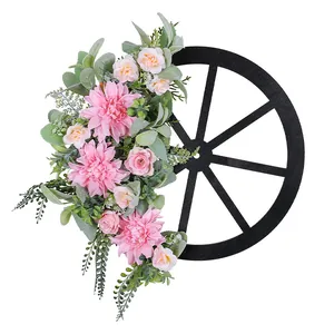 Rustic farmhouse decorative pink flower wagon wheel wreath with artificial green leaves.