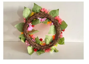 Macro view of handmade autumn wreath featuring pink daisies and lush green leaves