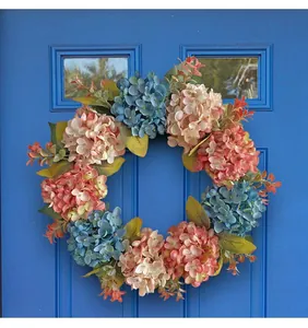 Detailed view of a blue and pink hydrangea floral wreath hanging on a blue door.