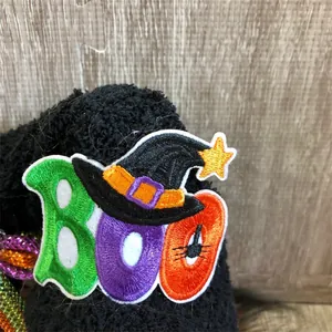 Close-up detail of Halloween BOO embroidered patch on a black plush gnome decoration