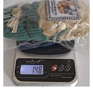 Detailansicht der 148 g schweren Harvest Festival Strickpuppe auf einer Digitalwaage
