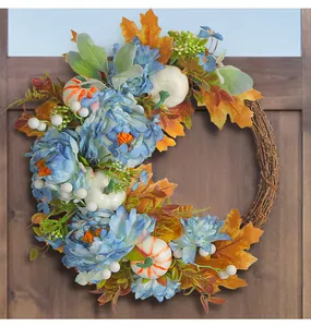 Detail view of harvest wreath with blue peonies, pumpkins and maple leaves on wooden door