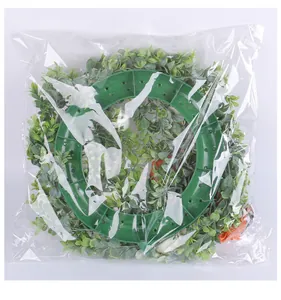 Kunstmatige oogstkrans met witte pompoenen in een transparante plastic verpakking