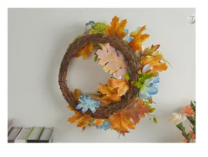 Decorative autumn harvest wreath with maple leaves and blue flowers on a white wall