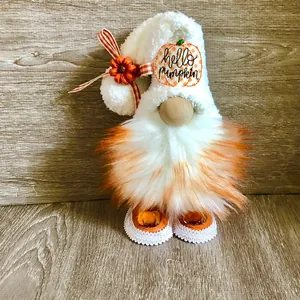 Close-up of autumn gnome doll with hello pumpkin patch and white fluffy hat