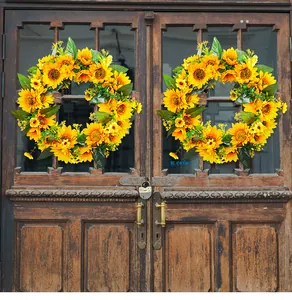 Vue détaillée de deux couronnes de tournesols artificiels sur une porte en bois rustique.