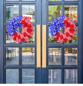 Coppia di ghirlande con bandiera americana appese a una porta per l'Independence Day.