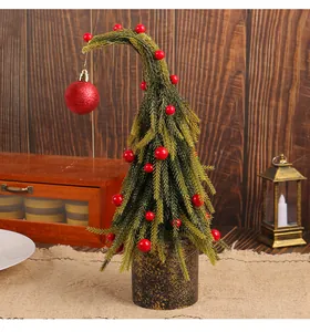 Detailed view of curved artificial Christmas tree with red berries on burlap surface