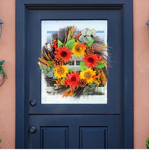 Decorative autumn sunflower wreath with pine cones on a dark navy blue front door