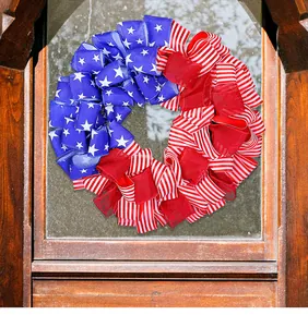 Dettaglio di una ghirlanda di nastri con bandiera USA su una porta di legno per l'Independence Day
