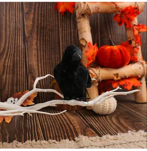 Detailed view of realistic black feathered crow on white branch for Halloween decoration
