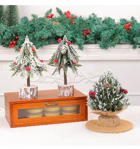 Detailed view of three mini Christmas trees with snow, red berries, and pine cones