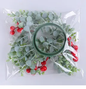 Nahaufnahme des Weihnachtskerzenrings mit roten Beeren und grünen Blättern in Klarsichtbeutel
