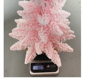 Dettaglio di un albero di Natale floccato rosa su una bilancia che pesa 607 grammi