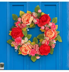 Élégante couronne de pivoines artificielles avec fleurs en soie rouges et roses sur porte bleue