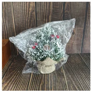 Detailed view of a mini Christmas tree with red berries in plastic packaging.