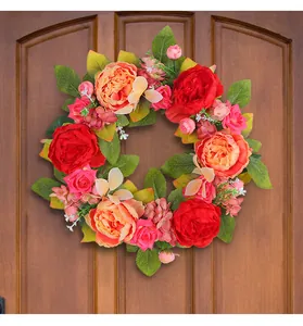 Vue détaillée d'une couronne de pivoines artificielles sur une porte en bois massif.