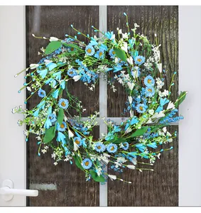 Beautiful blue daisy and berry floral wreath hanging on a white door for home decoration