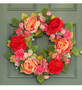 Vue détaillée d'une couronne de pivoines en soie rouge et rose avec des feuilles vertes