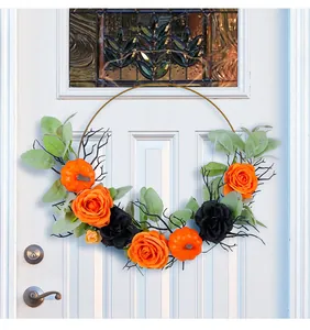 Ghirlanda di Halloween in ferro con zucche e rose appesa a una porta d'ingresso bianca