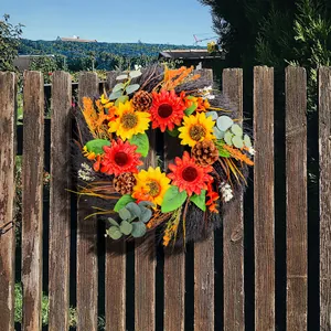 Autumn sunflower and pinecone wreath hanging on a rustic wooden garden fence