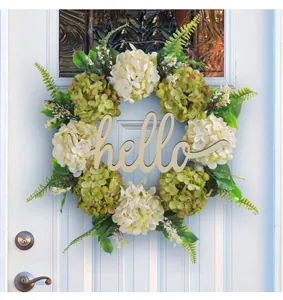 Beautiful artificial hydrangea floral wreath with hello wooden sign on a white front door