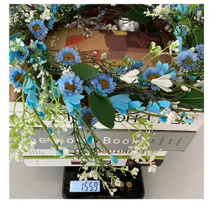 Close-up detail of a blue and white artificial wreath on a scale weighing 155.9g